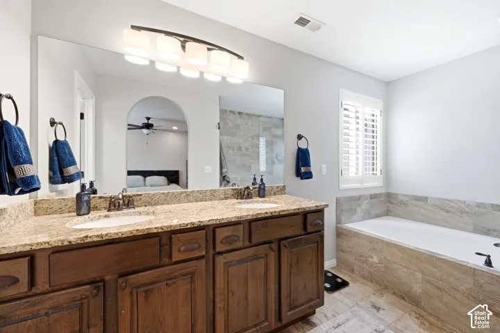 Dual vanity with granite countertop, wood-finish cabinetry, and undermount sinks