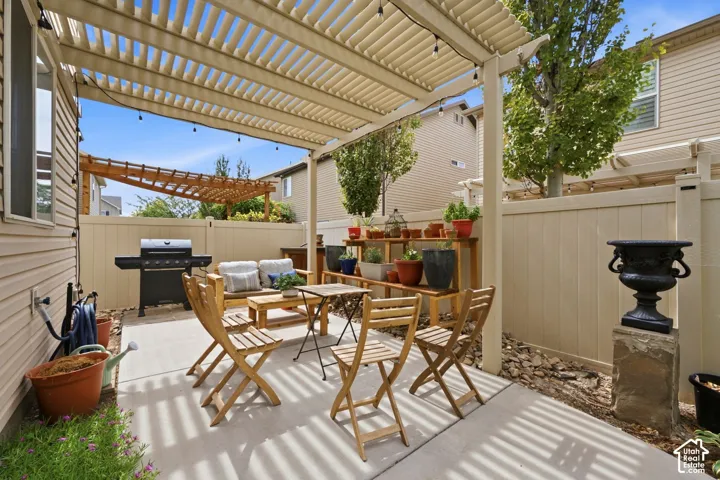 Patio featuring a slatted pergola, concrete paving, and light-colored fencing