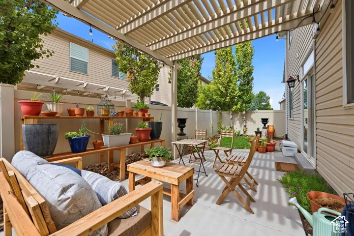 Outdoor patio featuring a slatted pergola, concrete flooring, and a privacy fence