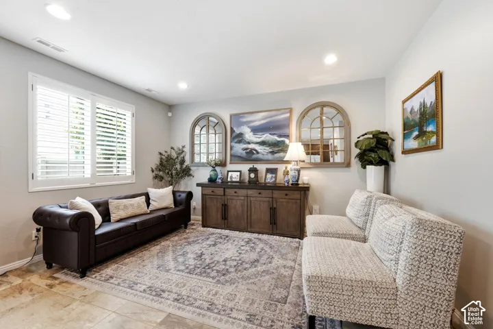 Recessed ceiling lighting, plantation shutters, tile flooring, and a built-in wood-finish console
