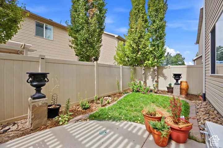 Paved patio with a manicured lawn, established privacy fencing, and planted garden beds