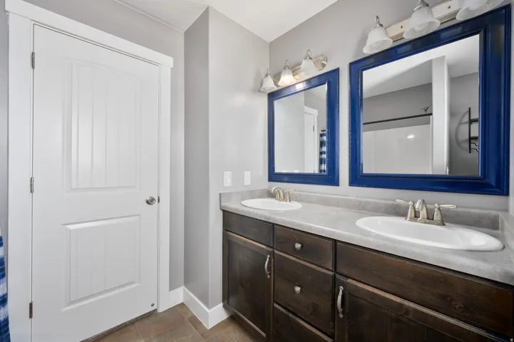 Dual vanities with integrated sinks, wood-finish cabinetry, and framed mirrors