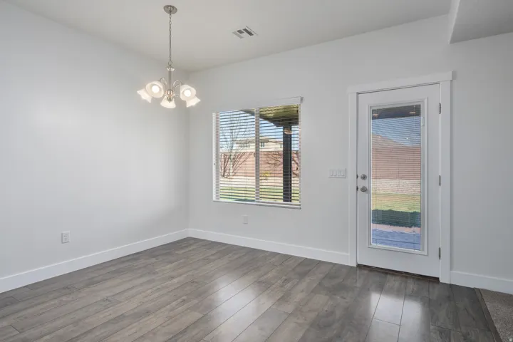 Wood-finish flooring, white walls, and a contemporary chandelier