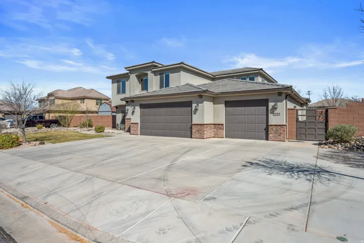 Stucco exterior with brick detailing, dual garage doors, and a concrete driveway