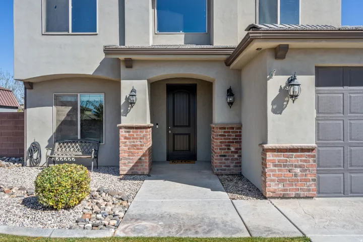 Stucco exterior with brick accents, arched entry, panel-style garage door, and decorative sconce lighting