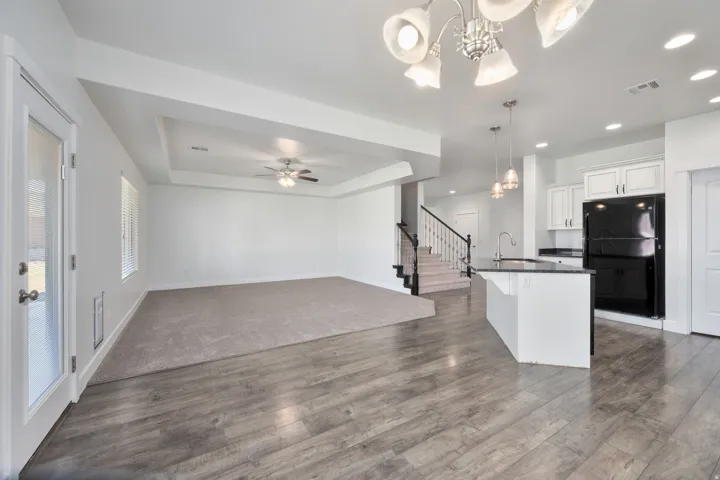 Open concept living space featuring wood-finish flooring, a kitchen island with pendant lighting, white cabinetry, and recessed lighting