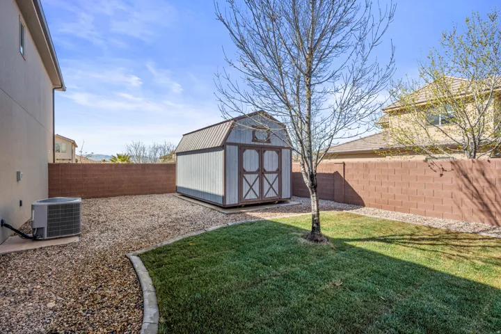 Gable-roof storage shed, full block wall perimeter, partial grass lawn, and gravel landscaping