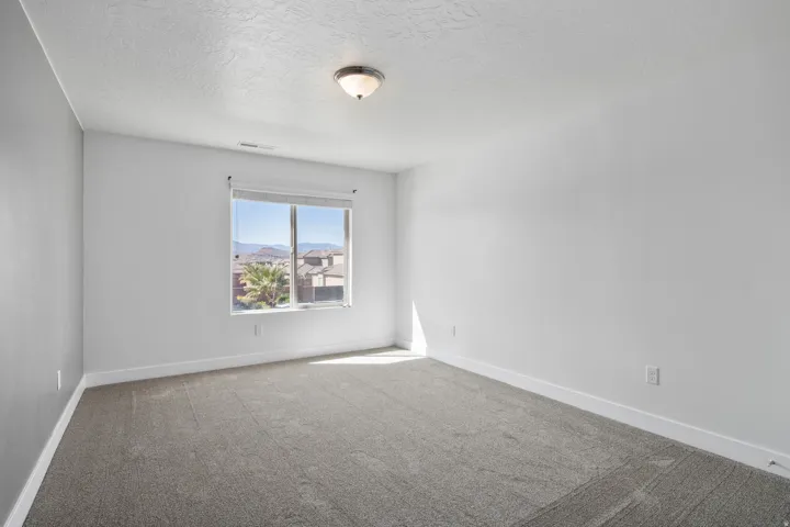 Carpeted room with a single window, a flush mount ceiling light fixture, and white wall finishes