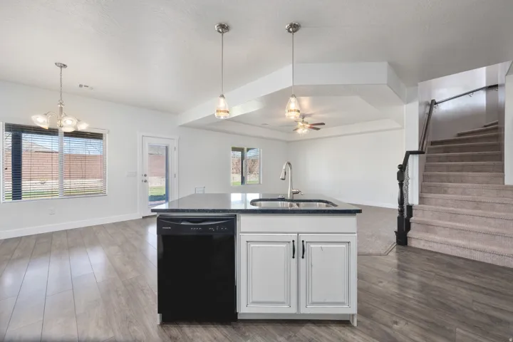 Kitchen island with integrated sink and dishwasher, wood-finish flooring, and pendant lighting