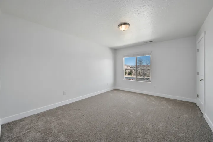 Neutral wall finishes, textured ceiling, flush mount lighting, and a single window with white trim