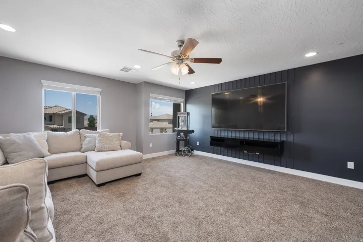 Carpeted living area featuring recessed lighting, a ceiling fan, and multiple windows