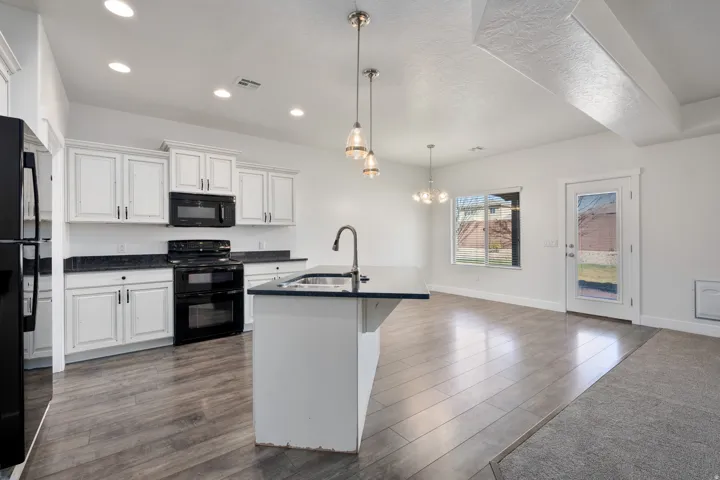 Kitchen featuring white cabinetry, dark countertops, and black appliances