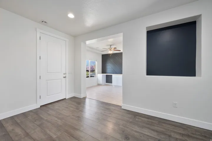 Wood-finish flooring throughout, recessed lighting, and a paneled entry door