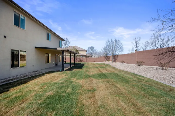 Expansive backyard featuring a manicured lawn, a full-length covered patio, and a privacy wall