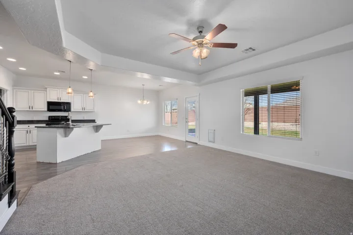 Spacious open-concept layout with tray ceilings, recessed lighting, and a ceiling fan