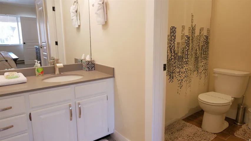 Vanity with a single basin sink, light-toned countertop, and white cabinetry