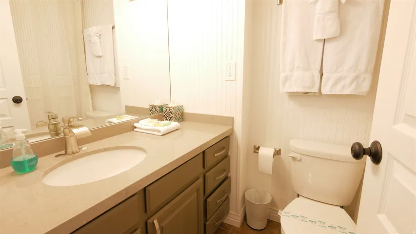 Vanity with integrated sink, brushed nickel faucet, large mirror, and beadboard wall paneling