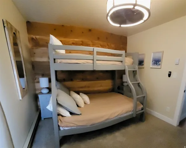 Wood-paneled accent wall, bunk bed with integrated ladder, drum-style ceiling light, and wall-to-wall carpeting