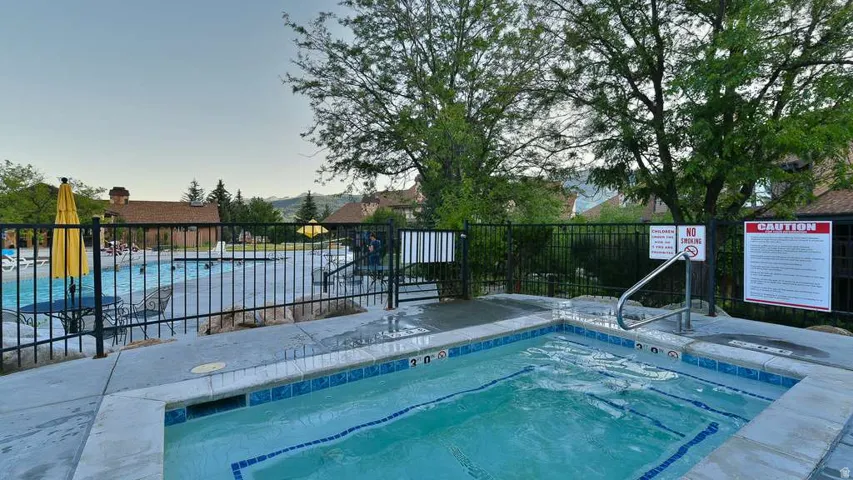 Integrated hot tub with handrail, adjacent to a large swimming pool