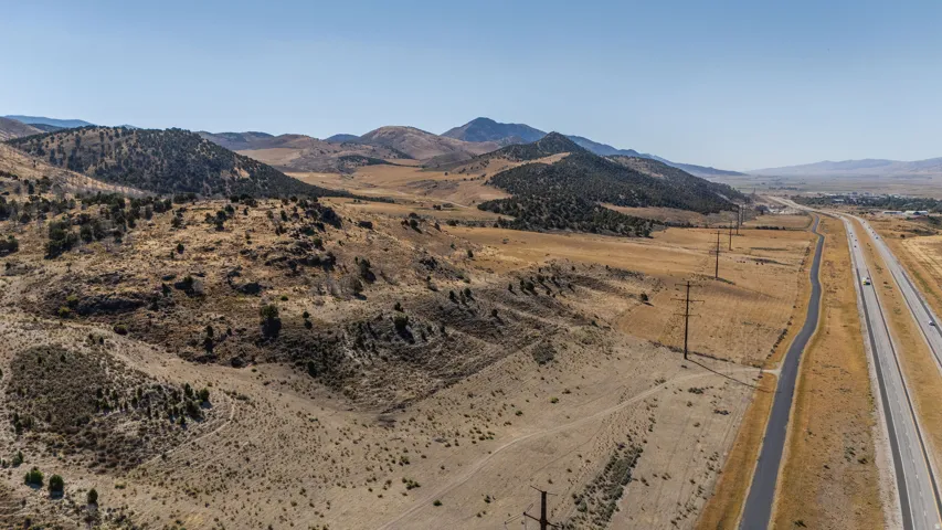 Expansive terrain featuring natural vegetation, distant mountains, and an adjacent multi-lane highway