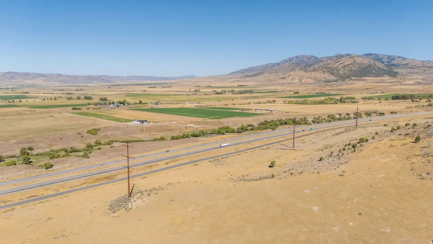 Expansive terrain with distant mountains, a multi-lane highway, and scattered vegetation