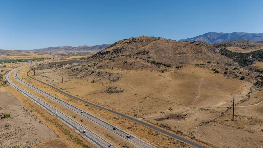 Expansive rural acreage with natural terrain, distant mountains, and direct highway access