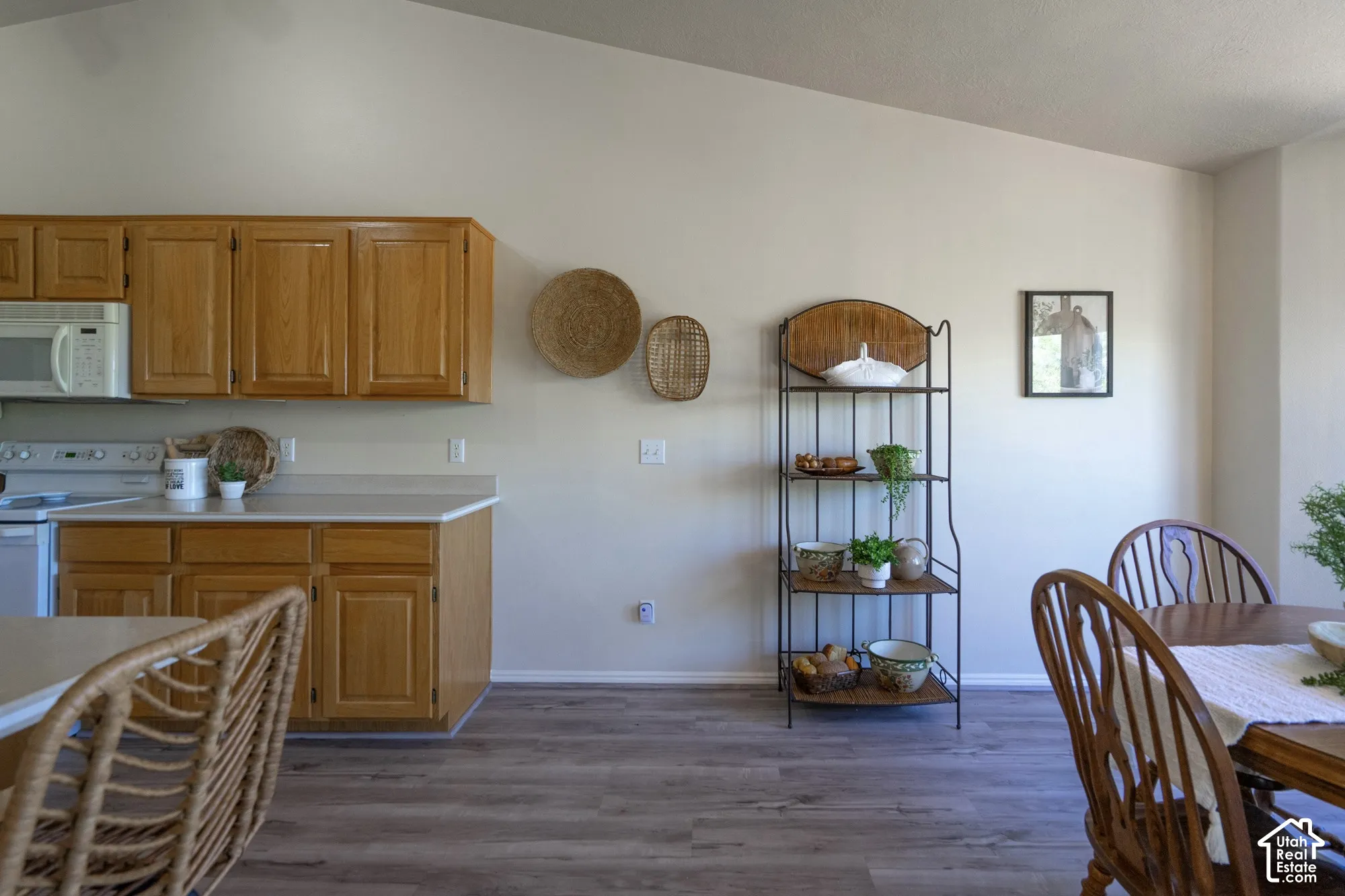 Bright, open-concept kitchen and dining area featuring wood-finish cabinetry, stainless steel appliances, wood-finish flooring throughout, and ample natural light