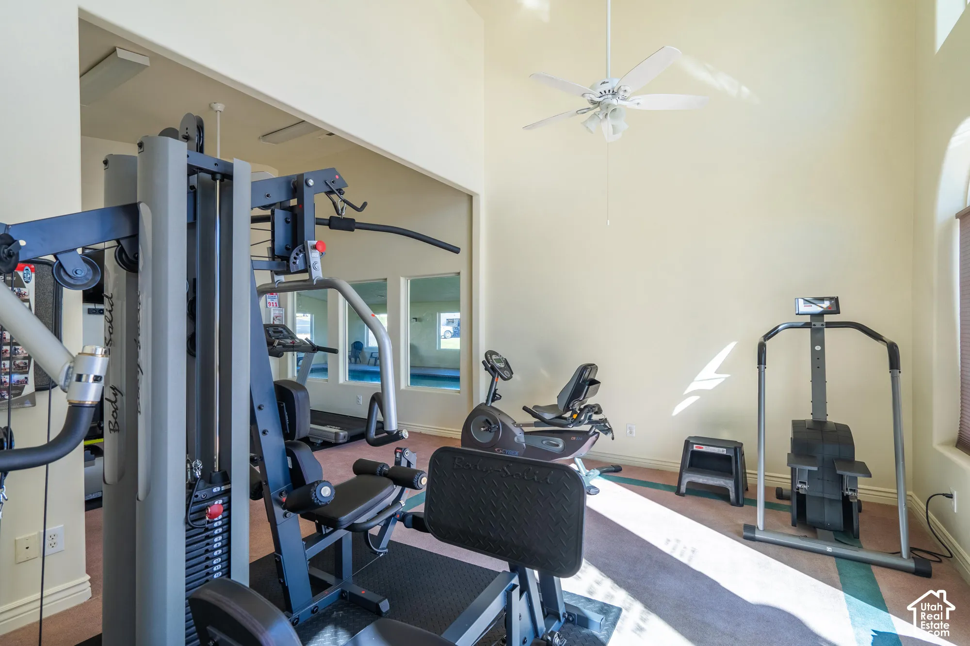 Fitness room featuring high ceilings, a ceiling fan, and arched window