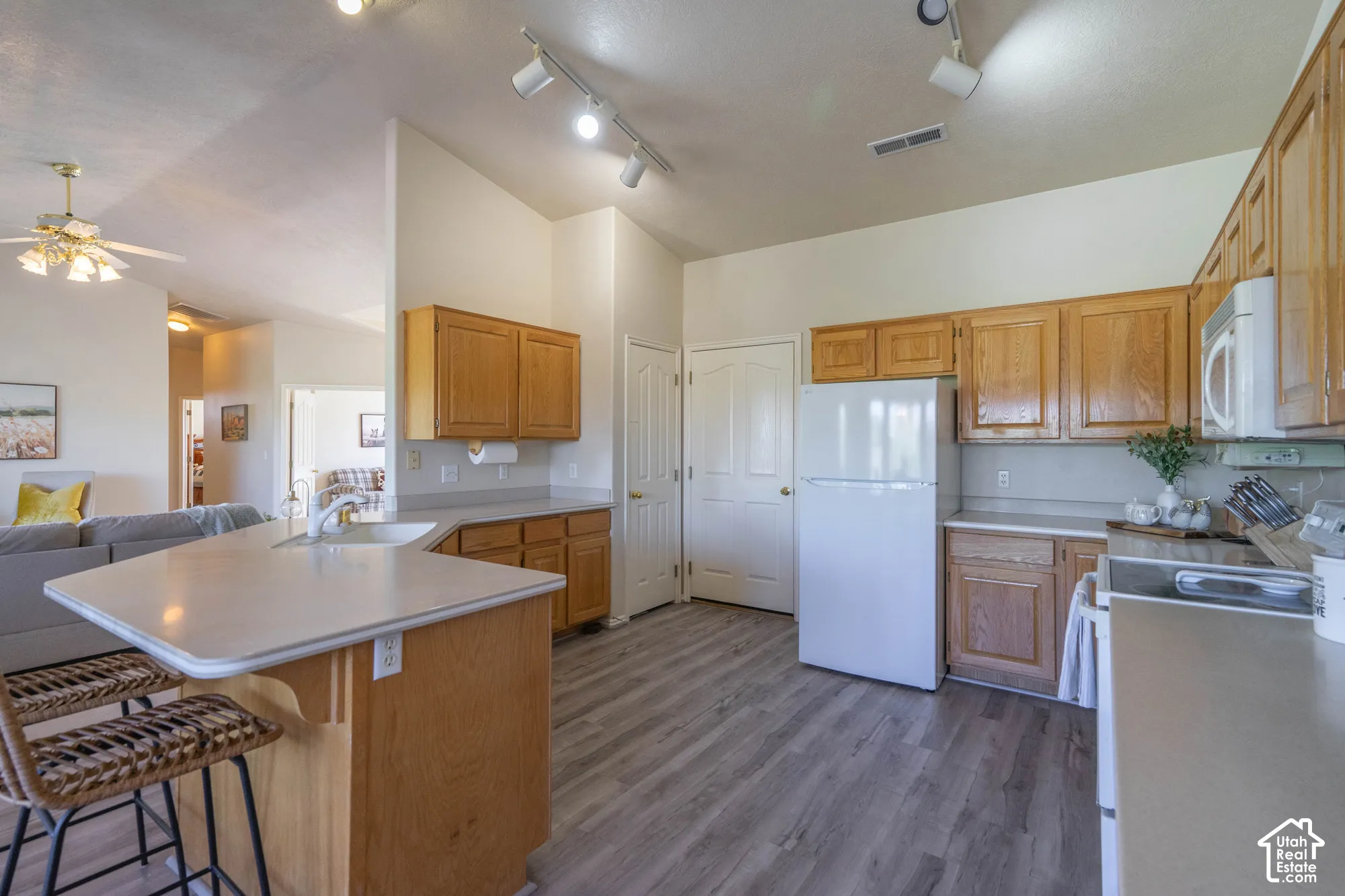 Kitchen featuring wood-finish cabinetry, track lighting, and a composite countertop with an integrated sink