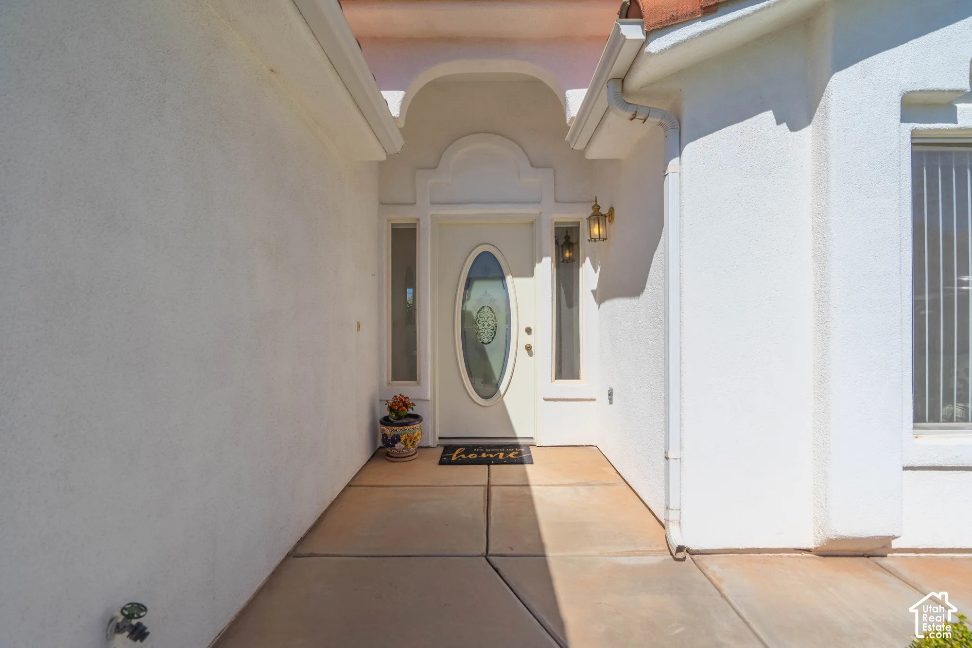 Arched entryway with a white oval-paneled door, flanking sidelight windows, and a brass-finished exterior light fixture