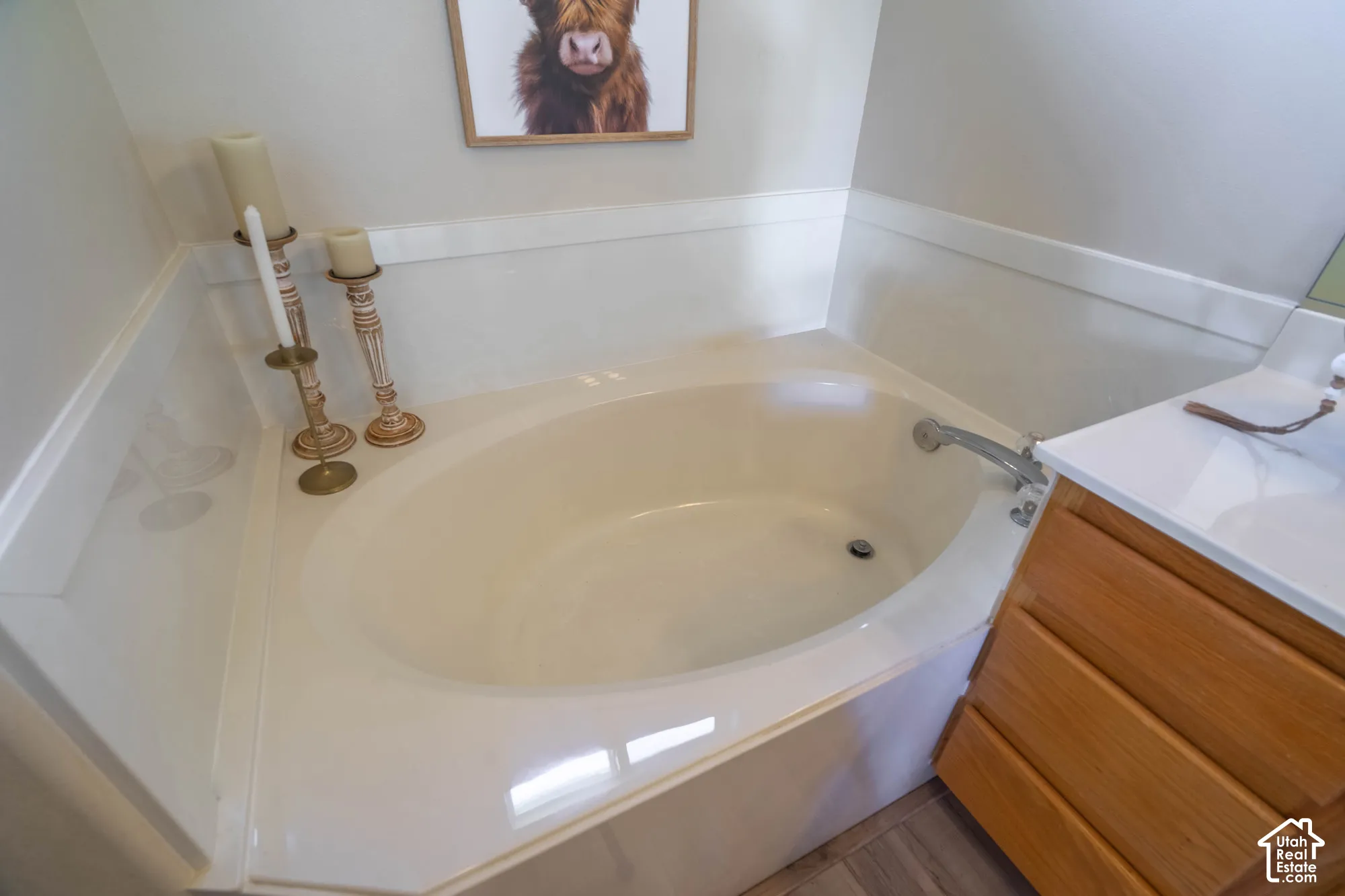 Corner soaking tub with a deck-mounted faucet and adjacent wood-finish vanity