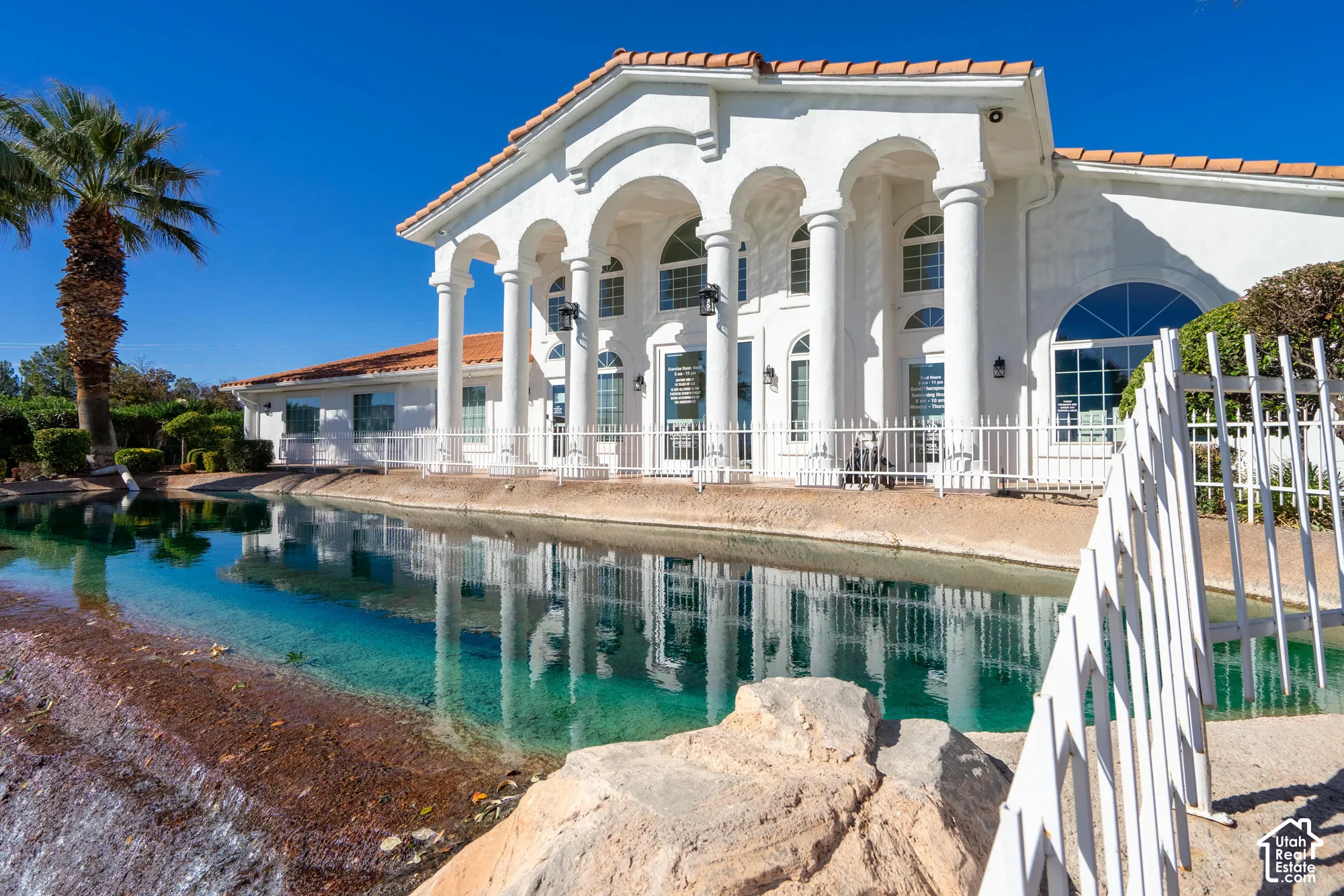 White stucco exterior with arched windows, multiple columns, and a terracotta tile roof