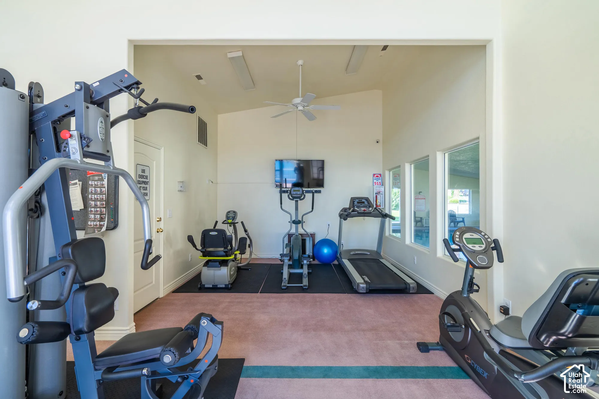 Vaulted ceiling with a ceiling fan, multiple windows, and light neutral wall paint