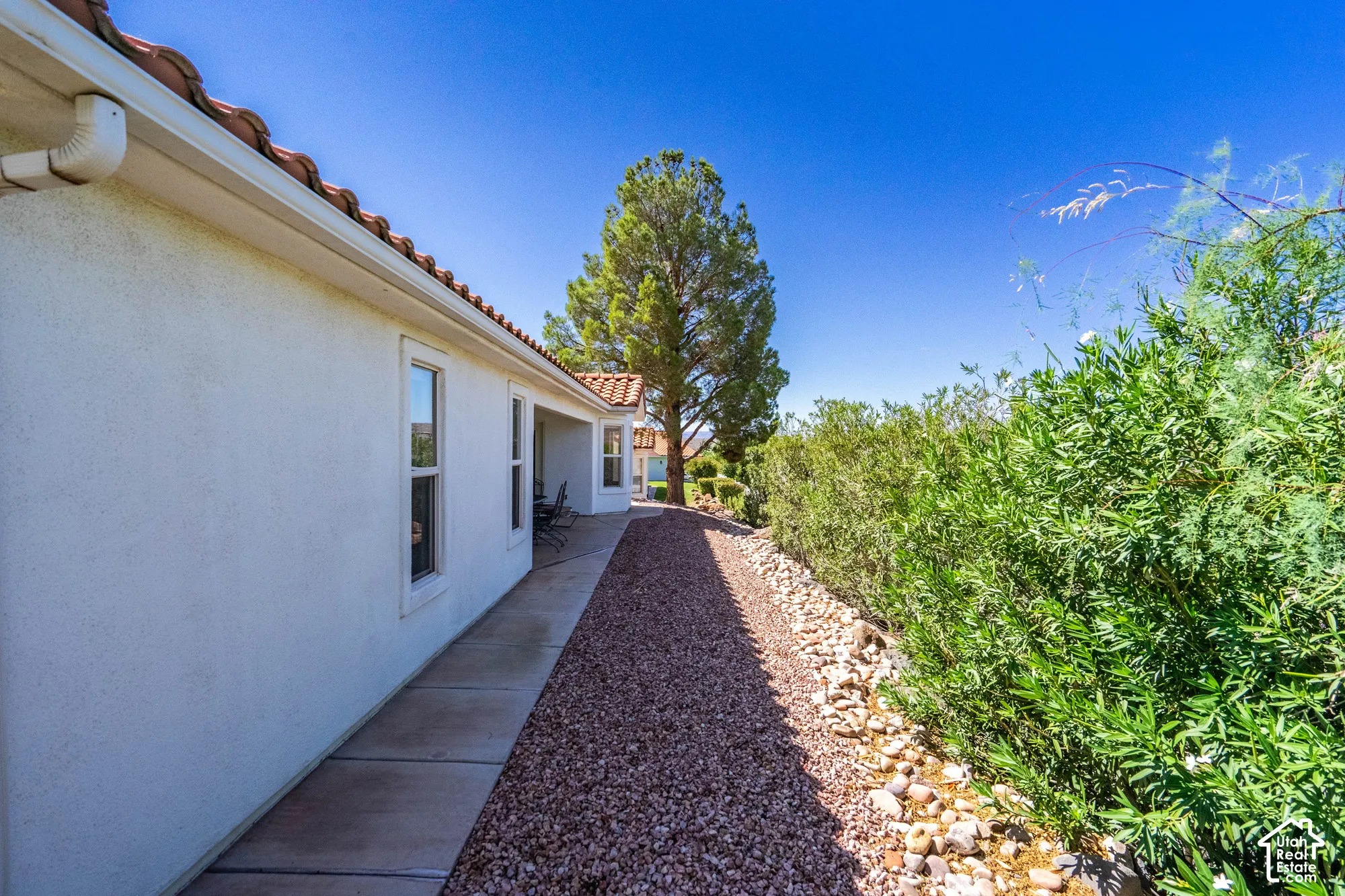 Stucco exterior with multiple windows and a concrete walkway