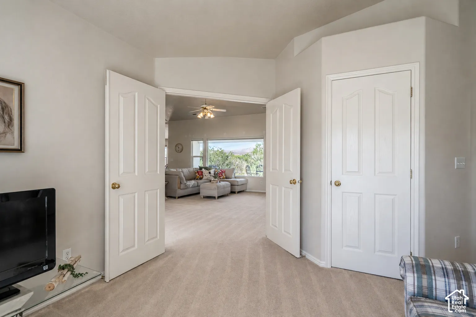Elegant double-door entry with six-panel white doors and brass hardware opens to a spacious interior featuring wood-finish flooring throughout
