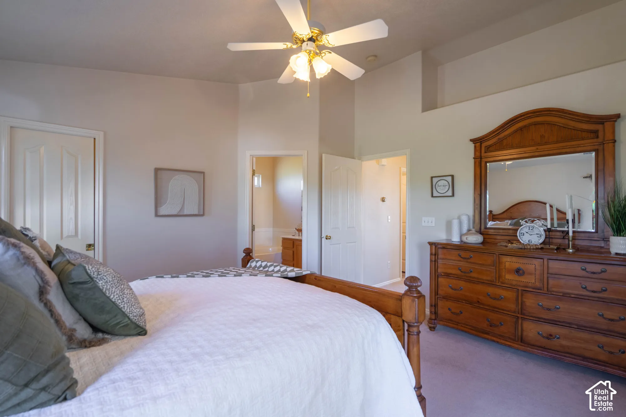 Vaulted ceiling with a ceiling fan, recessed wall alcove, and light-toned carpeting