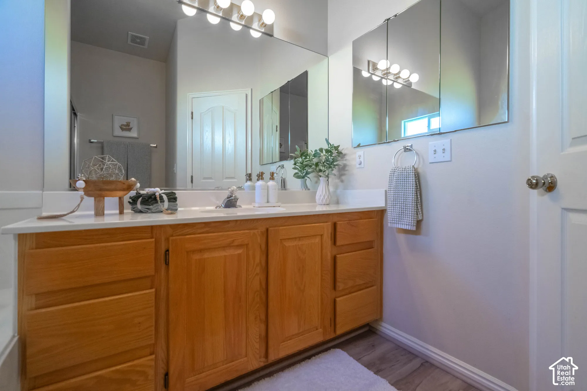 Expansive vanity with wood-finish cabinetry, a single basin sink, and a light-toned countertop