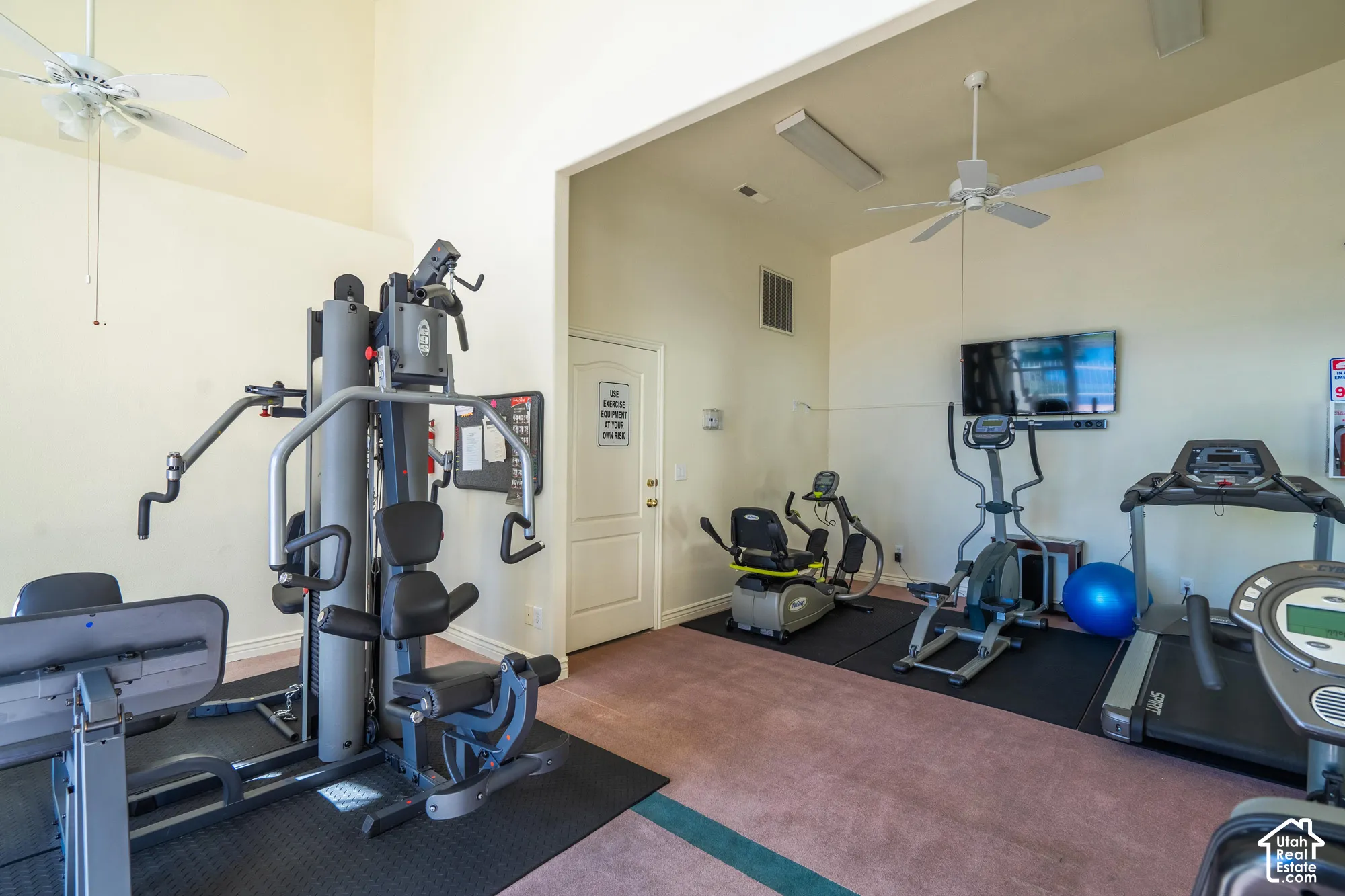 Dedicated fitness space featuring high ceilings, wall-mounted television, and ceiling fans