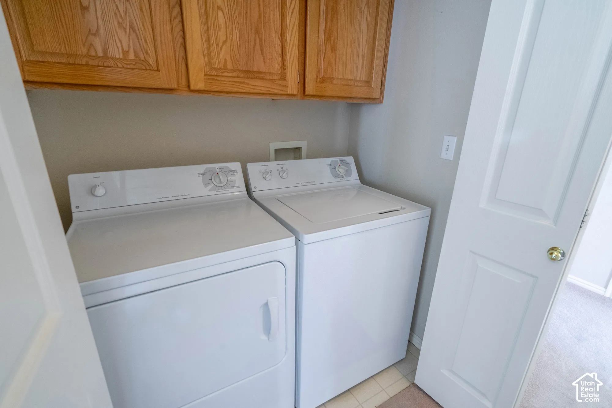 Upper cabinetry with wood-finish doors, and a full-size washer and dryer