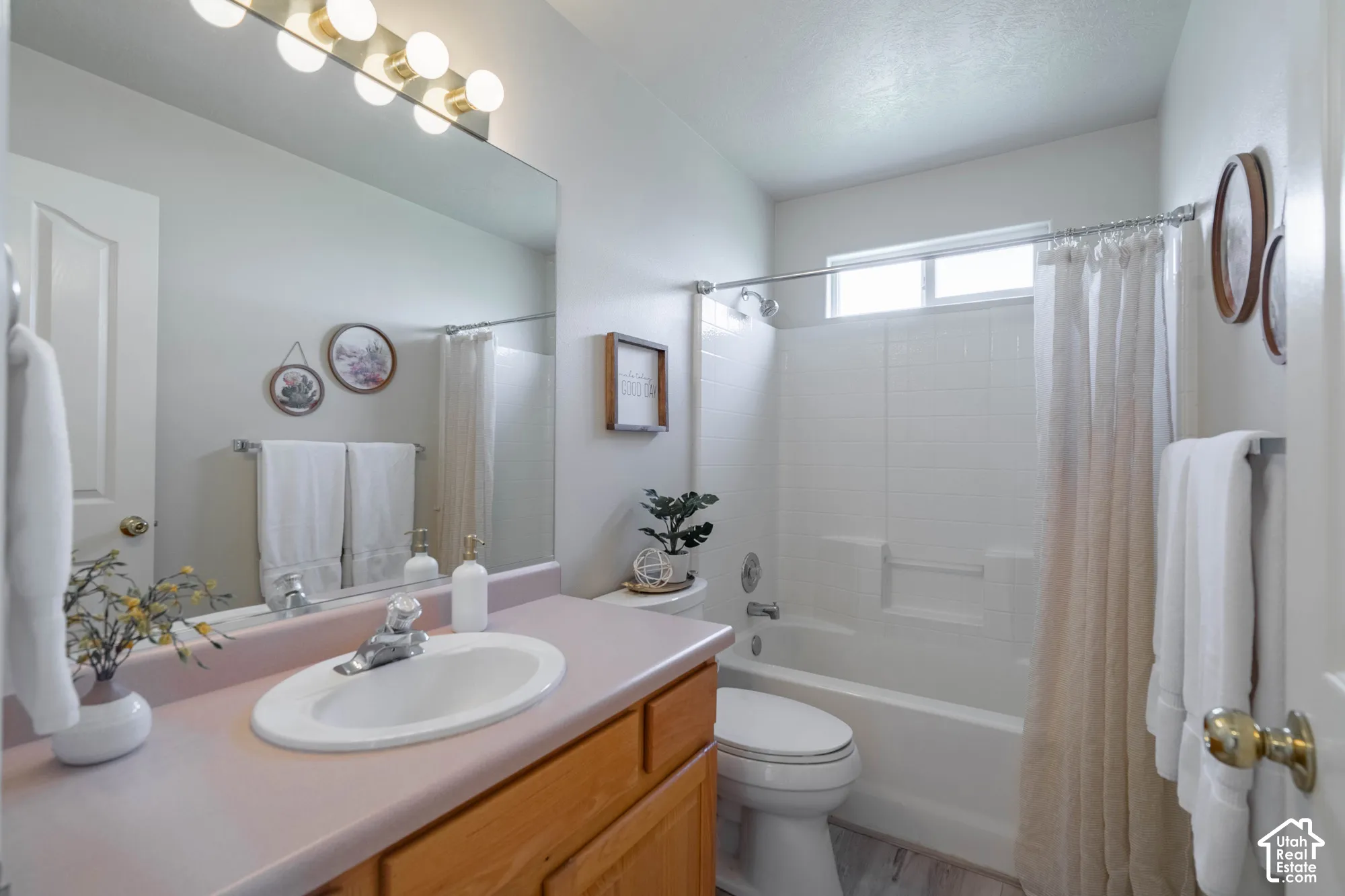 Single vanity with a light-colored countertop, integrated sink, and wood-finish cabinetry