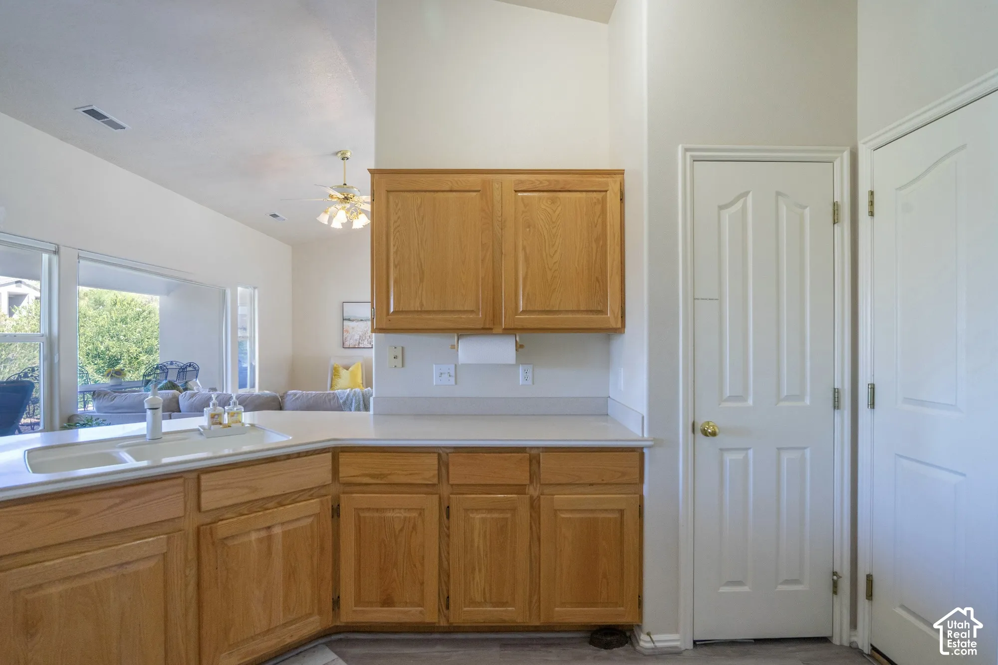 Light-toned cabinetry, light-colored countertops, single-basin sink, vaulted ceilings, and white doors