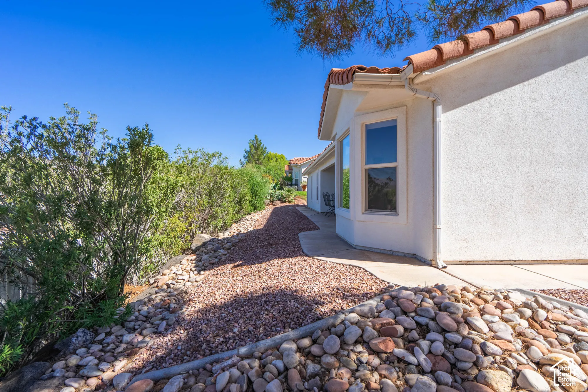 Stucco exterior with a terracotta tile roof, bay window, and concrete walkway