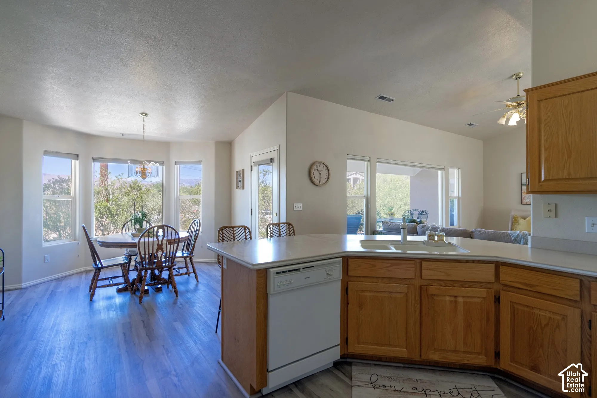 Kitchen with wood-finish flooring, wood cabinetry, white countertops, and an integrated white dishwasher
