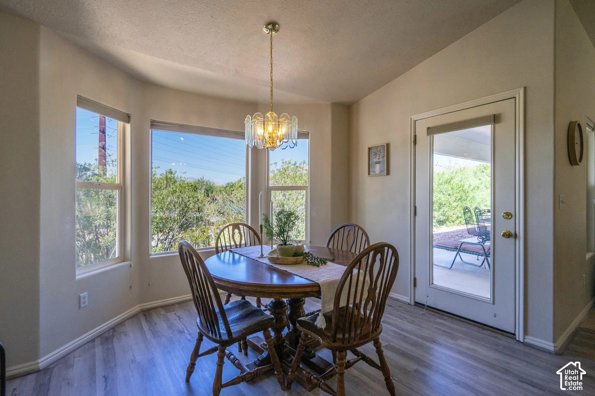 Bay window with multiple glass panes, wood-finish flooring, full-light exterior door, and a decorative chandelier