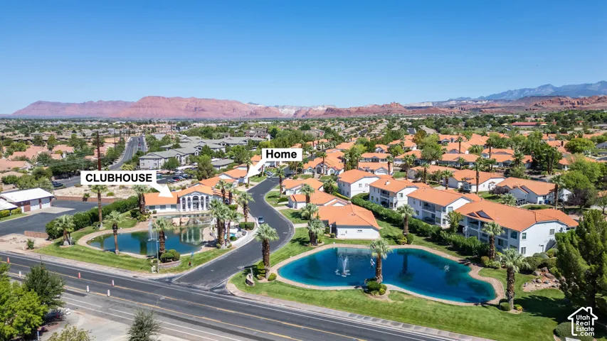 Community with multiple residential buildings featuring terra cotta roofs, mature palm trees, and two central ponds with fountains
