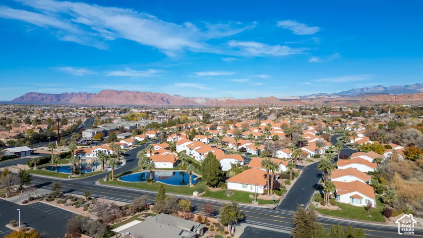 Community with residential structures featuring orange tile roofs, multiple water features, and palm trees