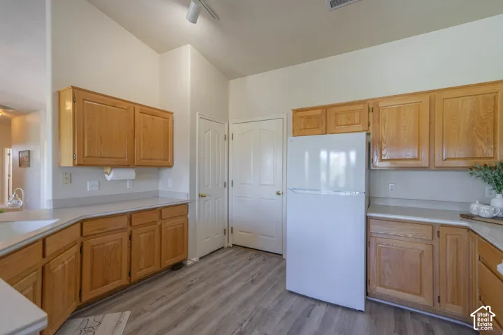 Kitchen featuring wood-finish cabinetry, light-toned countertops, and wood-finish flooring
