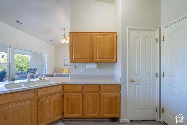 Kitchen area featuring wood-finish cabinetry, light-toned countertops, and a double basin sink