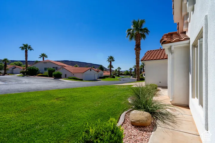 Stucco exterior with a terracotta tile roof, complemented by a manicured lawn and mature palm trees