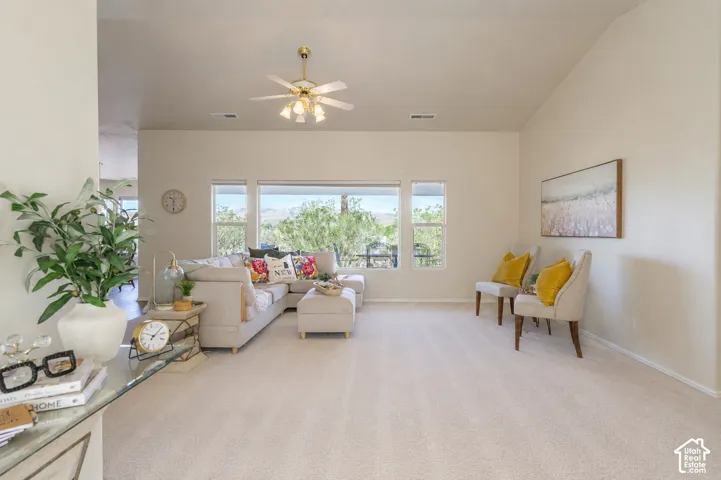 Vaulted ceilings, a multi-window wall, and a ceiling fan with integrated lighting